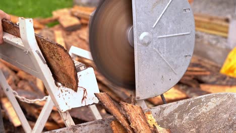 Man-using-crosscut-saw-to-cut-firewood-from-wooden-pine-planks---Closeup-of-saw-and-wood-falling-into-wheelbarrow-in-20-percent-slow-motion-and-blurred-background