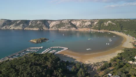 Aerial-view-of-Lopar-Croatia-travel-holiday-destination-with-little-port-for-luxury-yacht-and-lonely-remote-solitary-sandy-beach,-drone-reveal-seascape-with-hilly-cliff