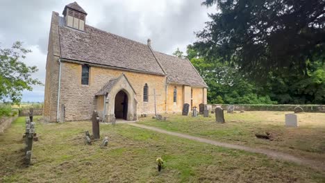 Wide-angle-view-of-church-with-typical-cemetery-in-Cotswolds-village-Hailes-in-Winchcombe---England
