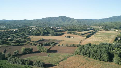 Drone-flight-over-agricultural-farm-in-Girona,-Barcelona-with-mountains-in-the-background
