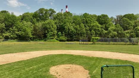 Ein-Niedriger-Blickwinkel-Auf-Ein-Leeres-Baseballfeld-An-Einem-Sonnigen-Tag-Mit-Blauem-Himmel-Und-Weißen-Wolken
