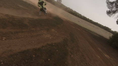 FPV-drone-chases-motocross-dirt-bike-rider-on-golden-sand-race-track