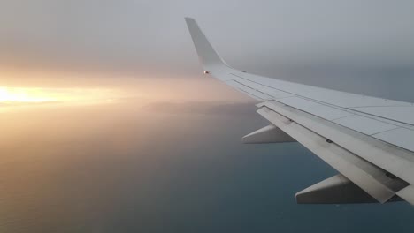 A-stunning-sunset-seen-from-the-airplane-window-looking-over-plane-wing,-land-and-ocean-of-New-Zealand-Aotearoa