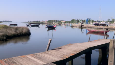 Schönes-Bild-Eines-Fischereihafens-Am-Fluss-Mit-Gehweg,-Der-In-Den-Fluss-Mündet,-Und-Traditionellen-Holzbooten,-Die-Festgemacht-Sind