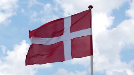 Bandera-Nacional-De-Dinamarca-Ondeando-Contra-El-Cielo-Azul-Brillante-Con-Nubes