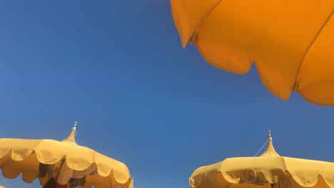 Right-to-left-panning-of-yellow-beach-umbrellas-and-clear-blue-sky-in-background,-Ukraine-color-concept