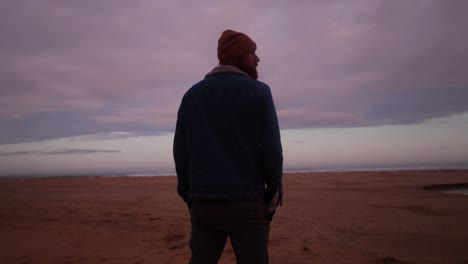 A-man-stands-and-looks-out-to-the-ocean-in-Australia-with-beautiful-pink-clouds-in-the-morning-sunrise