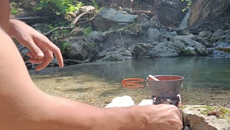 Guy-fires-hobo-cooker-in-nature-and-stir-pot-with-soup-on-top