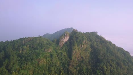 Aerial-view-showing-foggy-peak-of-forest-hill-in-the-morning---Menoreh-Hill,Indonesia