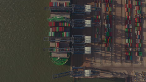 Top-down-drone-shot-over-cranes-loading-large-container-ship-at-Port-of-Felixstowe