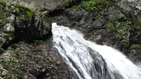 Ein-Mächtiger-Starker-Wasserfall-Mit-Vielen-Felsen-Herum,-Mit-Etwas-Grüner-Vegetation