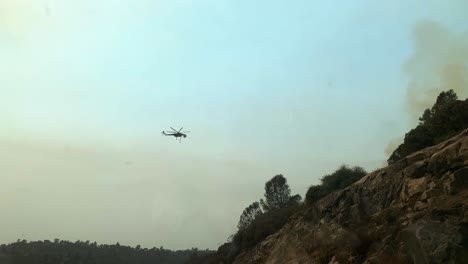 Toma-De-Conducción-Pov-De-Un-Helicóptero-Arrojando-Agua-Sobre-Un-Incendio-Forestal-En-Las-Tierras-Altas