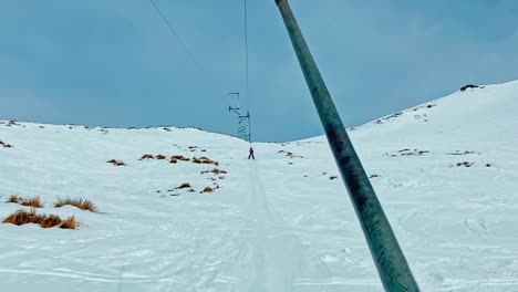 Hanmer-Springs-New-Zealand,-pointy-of-view-as-a-young-boy-rides-up-the-snow-covered-slopes-on-a-nut-cracker-ski-lift