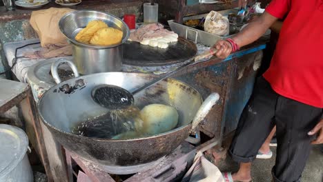 In-order-to-serve-Chole-Bhature-in-a-street-Dhaba,-the-chef-is-frying-and-cooking-Indian-cuisine-Poori-Puri-in-hot-oil-on-fire