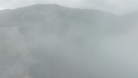 Aerial-of-low-fog-hanging-over-mountain-and-forest-trees
