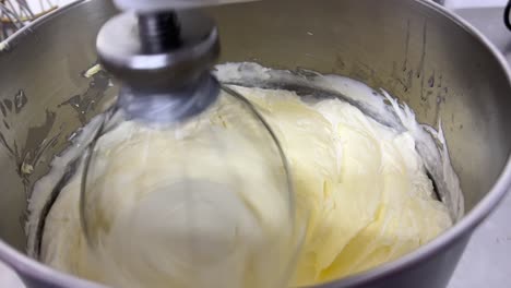 Fluffy-and-soft-Swiss-meringue-buttercream-pastry,-electric-mixer-mixing-and-beating-egg-white-and-sugar-until-it-is-glossy-peak-and-stiff-peak,-close-up-shot