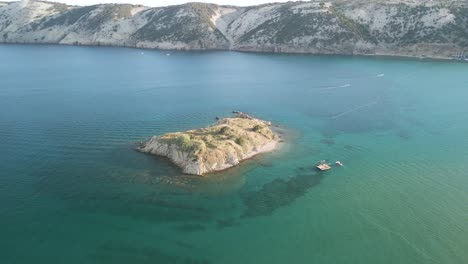 Aerial-of-luxury-sail-boat-yacht-moored-in-open-wide-sea-ocean-water-close-to-a-little-rocky-islet-exploring-snorkelling-and-diving-croatia