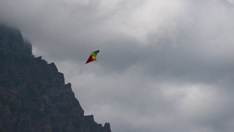 A-multicolored-kite-twirls-in-a-cloudy-and-windy-sky-above-the-Swiss-alps,-Obwalden