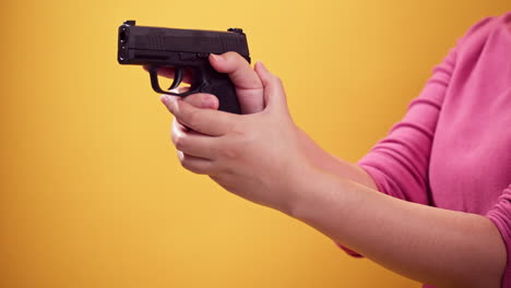 Nahaufnahme-Frau-Hält-Eine-Pistole,-Um-Die-Waffe-Auf-Hellgelben-Hintergrund-Zu-Zielen