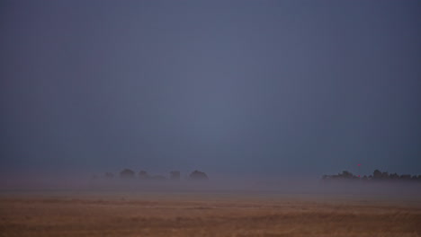 A-misty-fog-creeps-in-over-farmland-then-a-super-moon-rises-an-illuminates-the-countryside---time-lapse