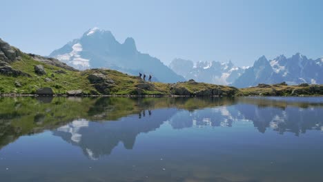 People-hiking-by-the-lac-blanc-with-reflections-of-the-mountains,-in-the-valley-of-chamonix,-in-france-in-a-sunny-day