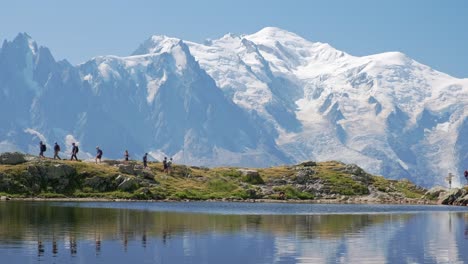 Gente-Caminando-Con-Reflejos-De-Las-Montañas,-Y-Detrás-De-La-Vista-Del-Mont-Blanc,-En-El-Valle-De-Chamonix,-En-Francia-En-Un-Día-Soleado