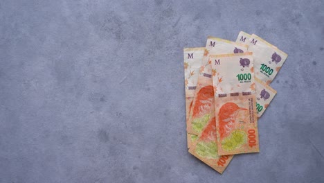 Person-Wirft-$1000-Argentinisches-Bargeld-Auf-Den-Tisch