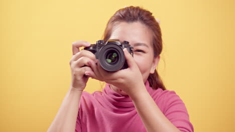 Wunderschöne-Junge-Asiatische-Frau-In-Einem-Studio,-Das-Mit-Einer-Digitalkamera-Mit-Kopierraum-Für-Werbung-über-Einem-Isolierten-Gelben-Hintergrund-Gedreht-Wurde