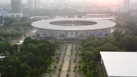 Walkway-in-GBK-Park-leading-to-the-sports-stadium-in-Jakarta-Indonesia-at-sunset,-aerial
