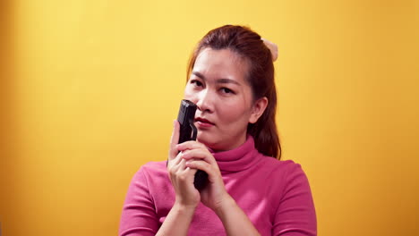 Series-Asian-woman-with-a-handgun-and-puts-a-magazine-to-aim-the-gun-ready-to-self-defense-on-bright-yellow-background