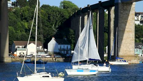 A-Tall-Sailboat-Sails-Under-the-Tamar-and-Royal-Albert-Bridge-Between-Devon-and-Cornwall