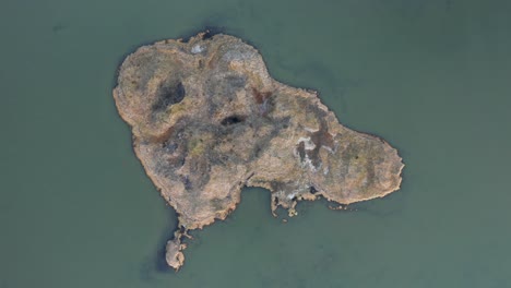 Small-little-grass-island-in-fresh-water-lake-near-Sandvik-beach,-aerial