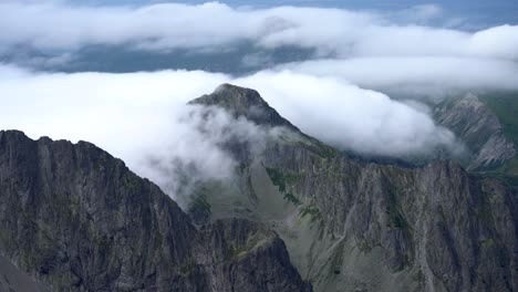 Slow-advection-fog-split-by-a-mountain-peak-cascades-down-bare-jagged-slopes,-the-Tatra-Mountains,-time-lapse