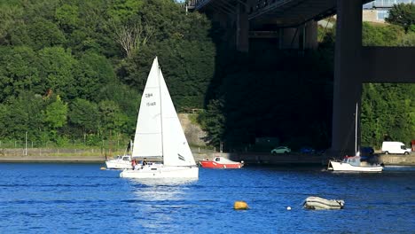 A-Tall-Sailboat-Sailing-Under-the-Tamar-Bridge-Between-Devon-and-Cornwall-on-a-Summers-Day-in-England