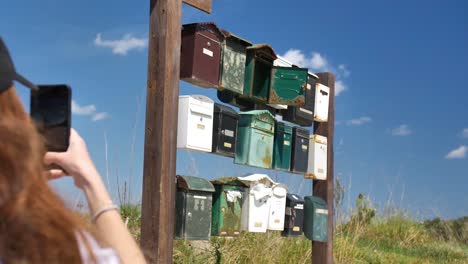 A-woman-photographs-old-mailboxes-on-a-wooden-wall-in-the-middle-of-nature-in-Mallorca