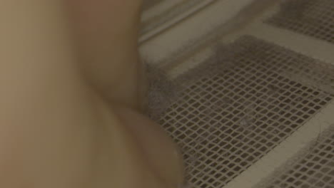Macro-shot-of-dust-and-lint-in-clothes-dryer-being-removed-by-hand