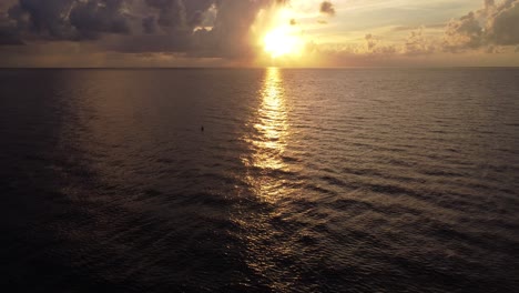 Ein-Malerischer-Sonnenaufgang-Oder-Sonnenuntergang-über-Dem-Ozean-Mit-Blick-Auf-Den-Horizont-Von-Einer-Luftdrohne,-Die-In-Richtung-Sonnenlicht-Fliegt