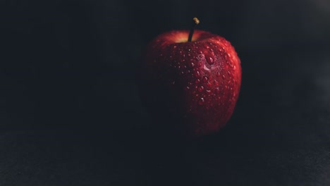 Forbidden-fruit-concept-represented-with-a-red-apple-on-a-black-background-with-copy-space,-fruit-of-the-sin