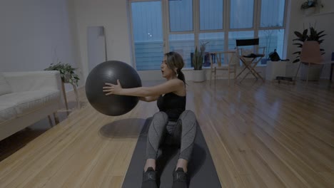 A-static-shot-of-an-Hispanic-woman-doing-at-home-work-outs-with-a-medicine-ball