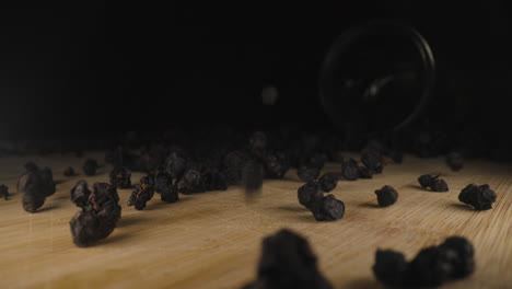 Dried-European-blueberry-Vaccinium-myrtillus-falling-on-wooden-table,-close-up-of-bilberry-fresh-organic-dehydrated-fruit