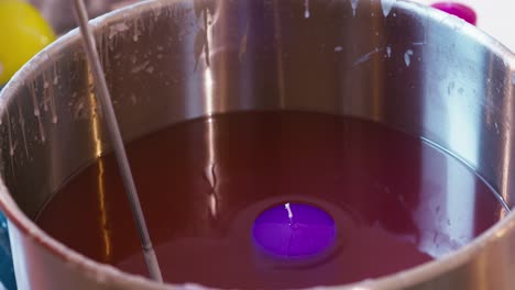 Dipping-a-purple-candle-in-liquid-wax