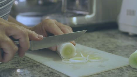 Detail-of-a-woman-cutting-a-leek-into-rounds-using-a-sharp-knife