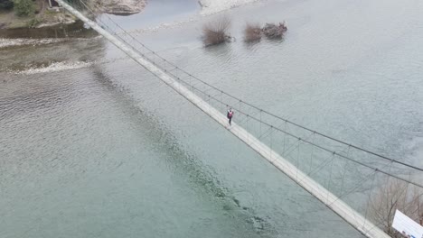 Girl-walking-on-hangway-over-the-river---drone-view