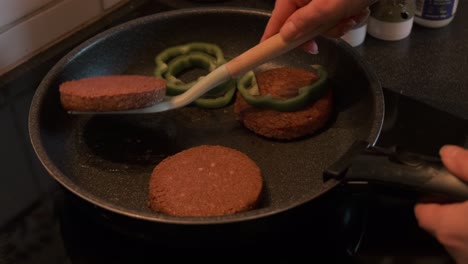 Cook-cooking-veggie-burgers-with-green-pepper-on-a-stove-in-4k-slow-motion