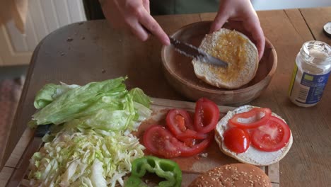 Cook-preparing-a-delicious-veggie-burger-adding-gherkin-sauce-in-4K-slow-motion