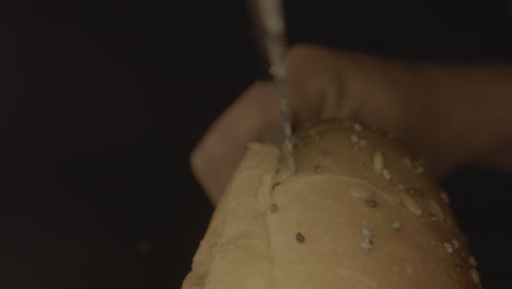 Macro-shot-of-hamburger-bun-being-cut-open-with-bread-knife