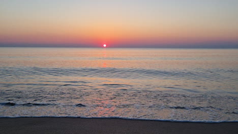 Calm-water-surface-and-sea-waves-splash-on-sandy-beach-at-sunrise-1