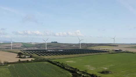 Windkraftanlagen-Mit-Sonnenkollektoren-Auf-Grünen-Feldern-In-Der-Nähe-Von-Saint-New-East-Landschaft-In-Cornwall,-England,-Vereinigtes-Königreich