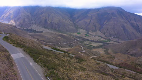 AERIAL---Cuesta-del-Obispo-hills-and-valley-in-Salta,-Argentina,-rising-tilt-down