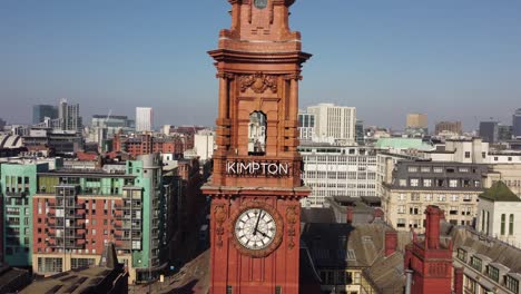Aerial-drone-flight-through-the-central-archway-of-the-Refuge-Building-Clock-Tower-on-Oxford-Road-in-Manchester-City-Centre-showing-a-view-of-the-surrounding-rooftops